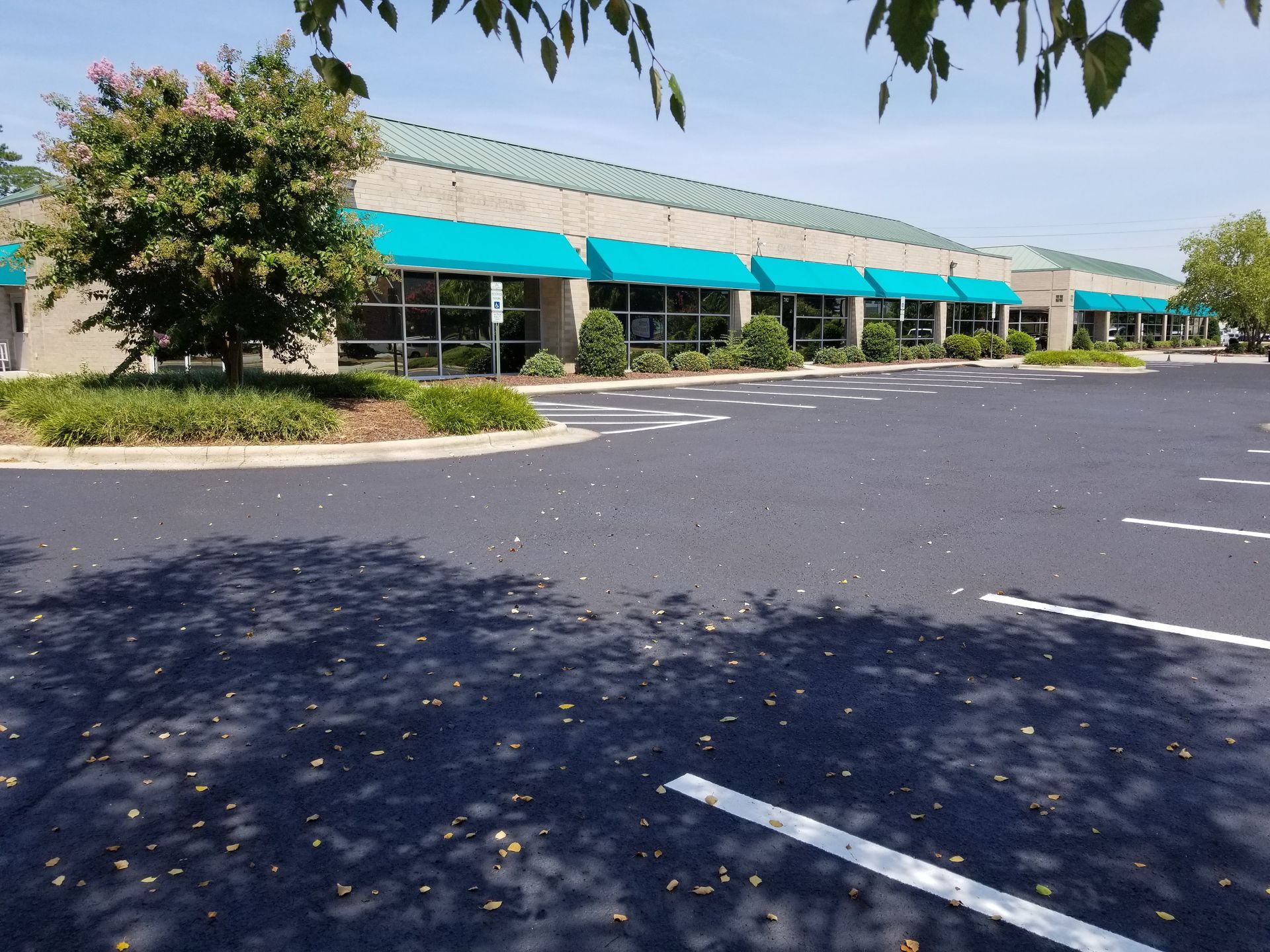 Building with teal awnings and a parking lot on a sunny day.
