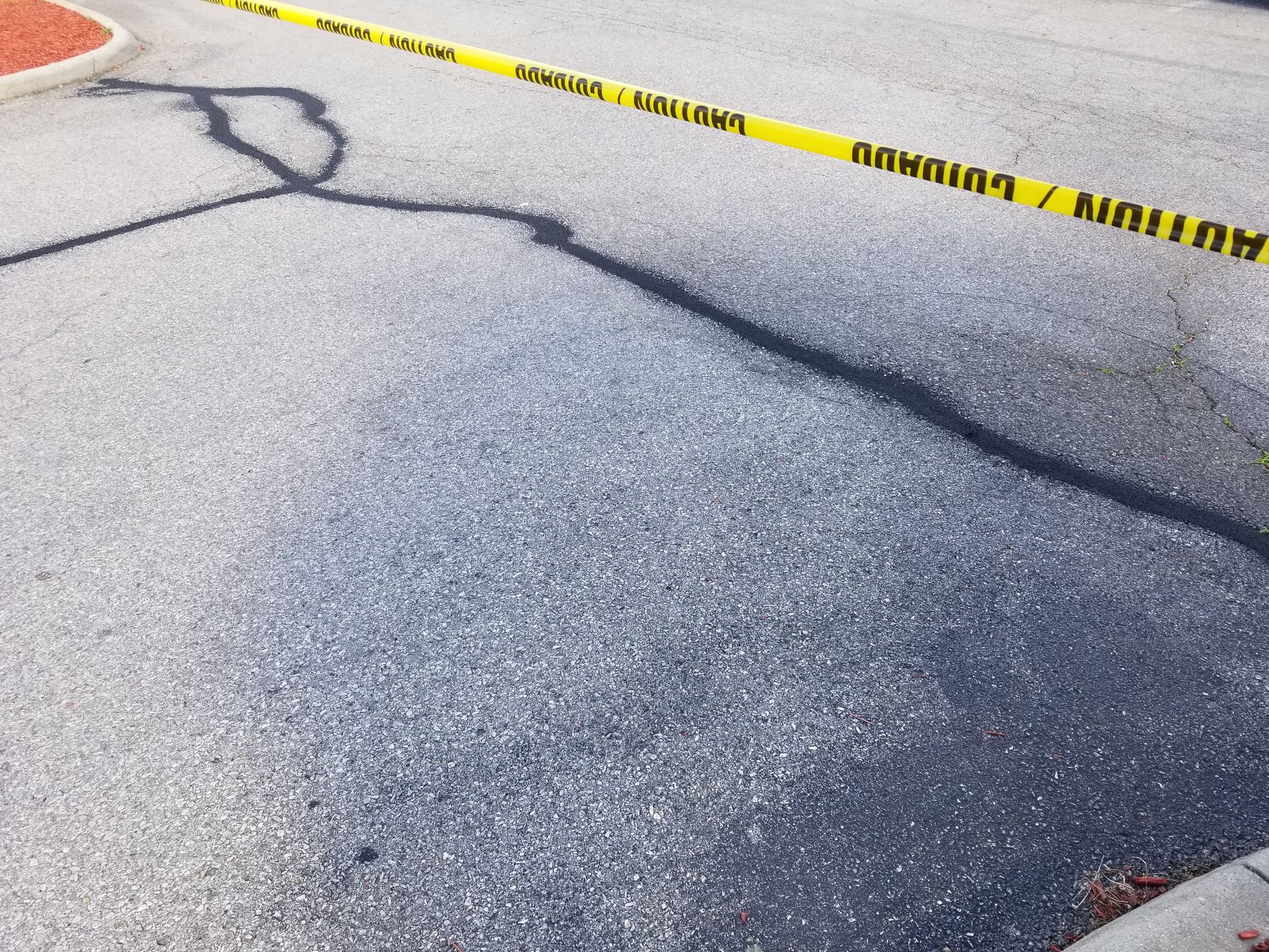 Yellow caution tape stretched across asphalt.