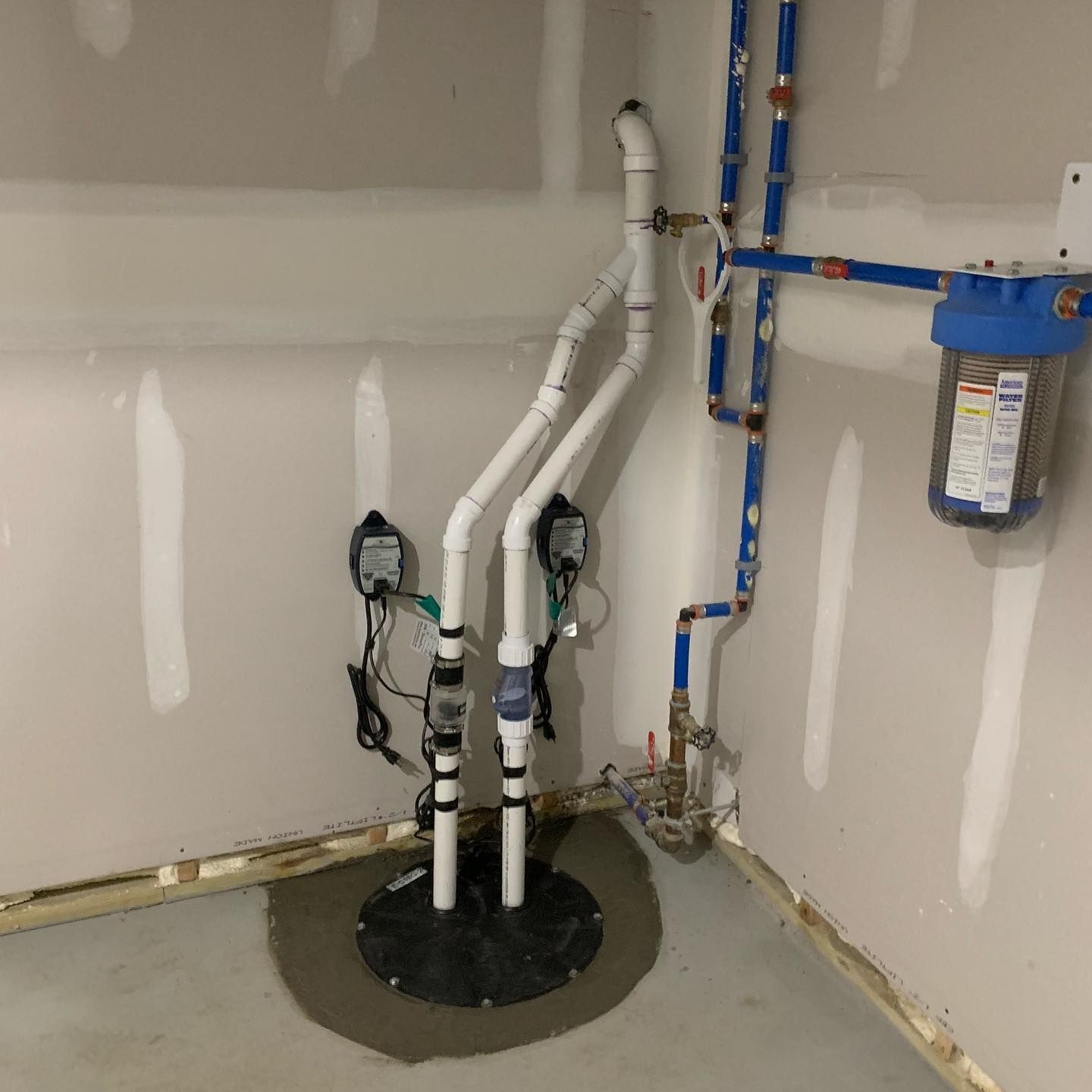 Sump pump system with pipes and water filter in a basement corner.