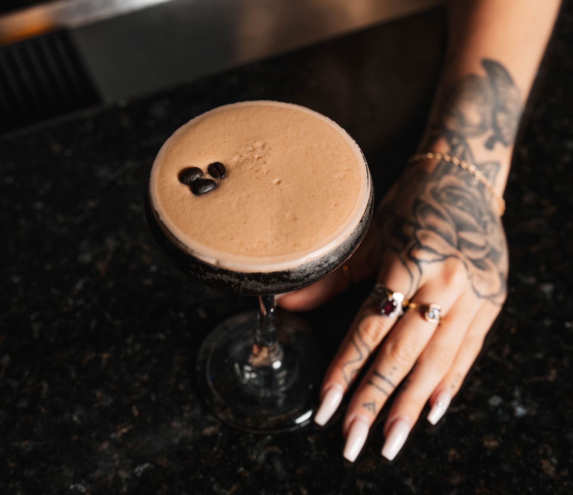 A woman with a tattoo on her hand is holding a martini