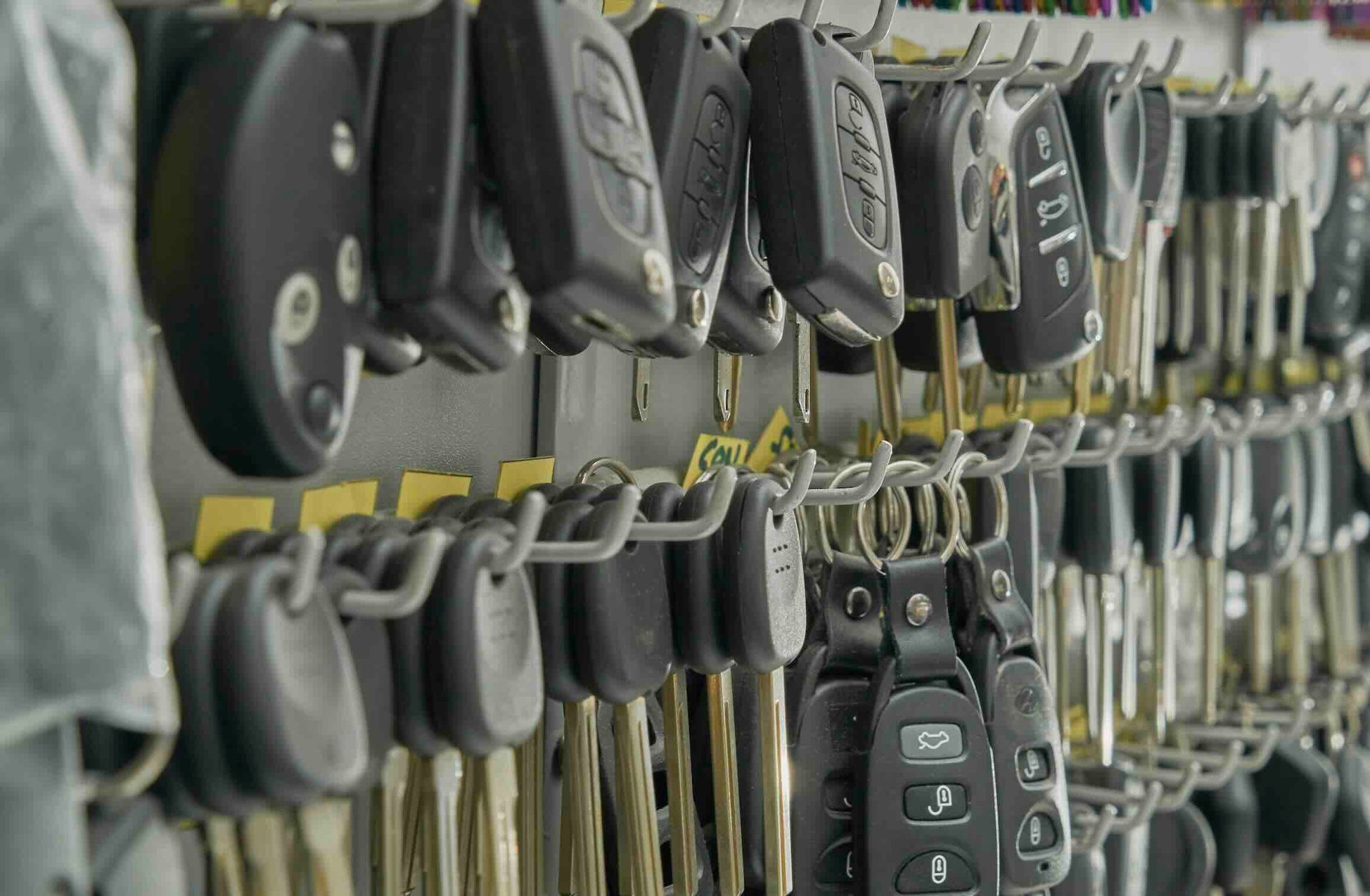 A wall rack holding a large collection of car keys and key fobs in a shop setting.