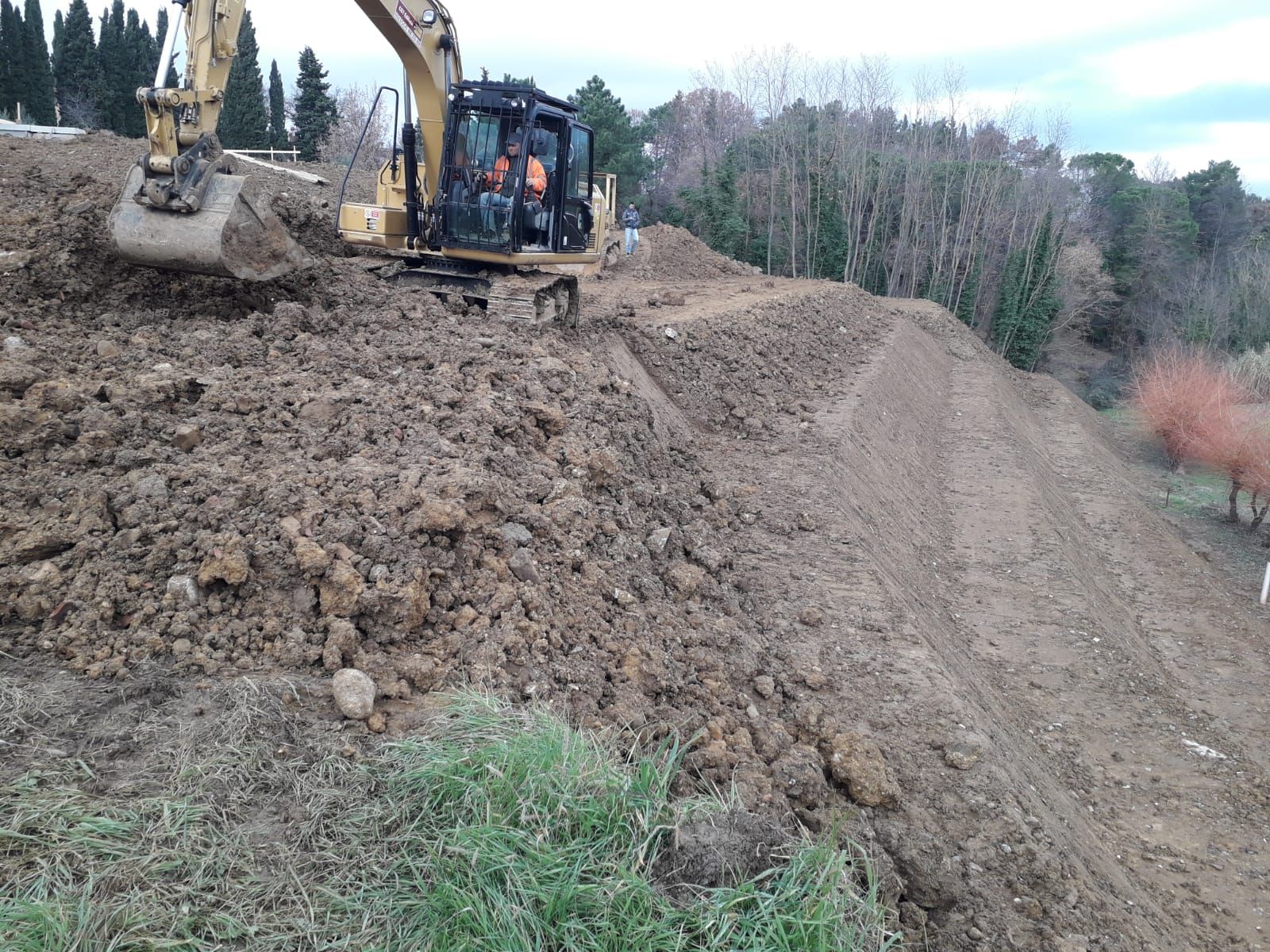 Una ruspa sta spostando terra sulla cima di una collina.