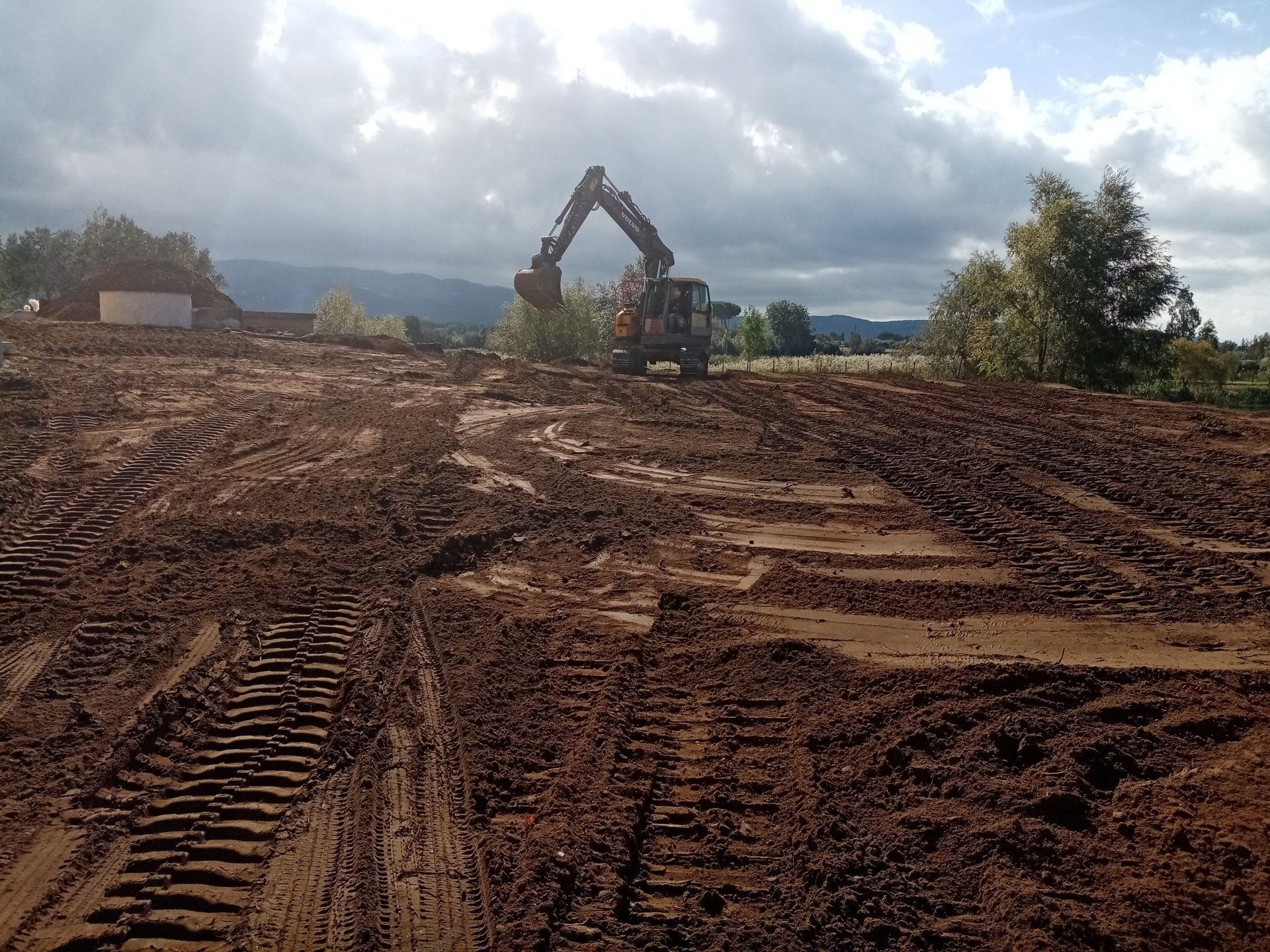 Un grande escavatore sta lavorando in un campo fangoso