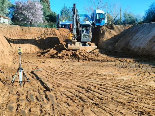 Una ruspa sta scavando una buca nel terreno di un cantiere edile.