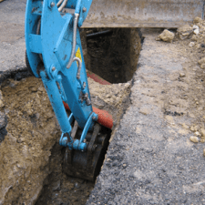 Un escavatore blu sta scavando una buca nel terreno