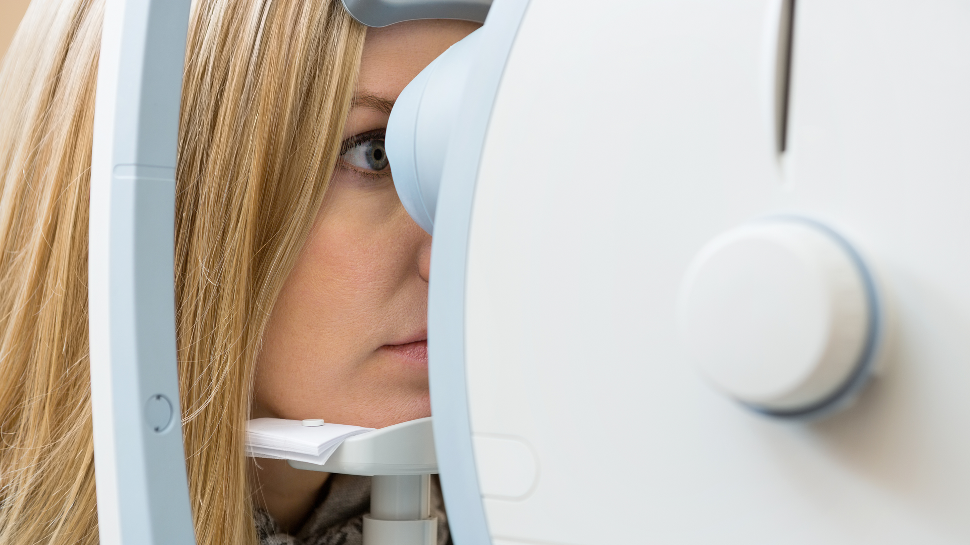 A woman is trying on glasses in front of an eye chart.