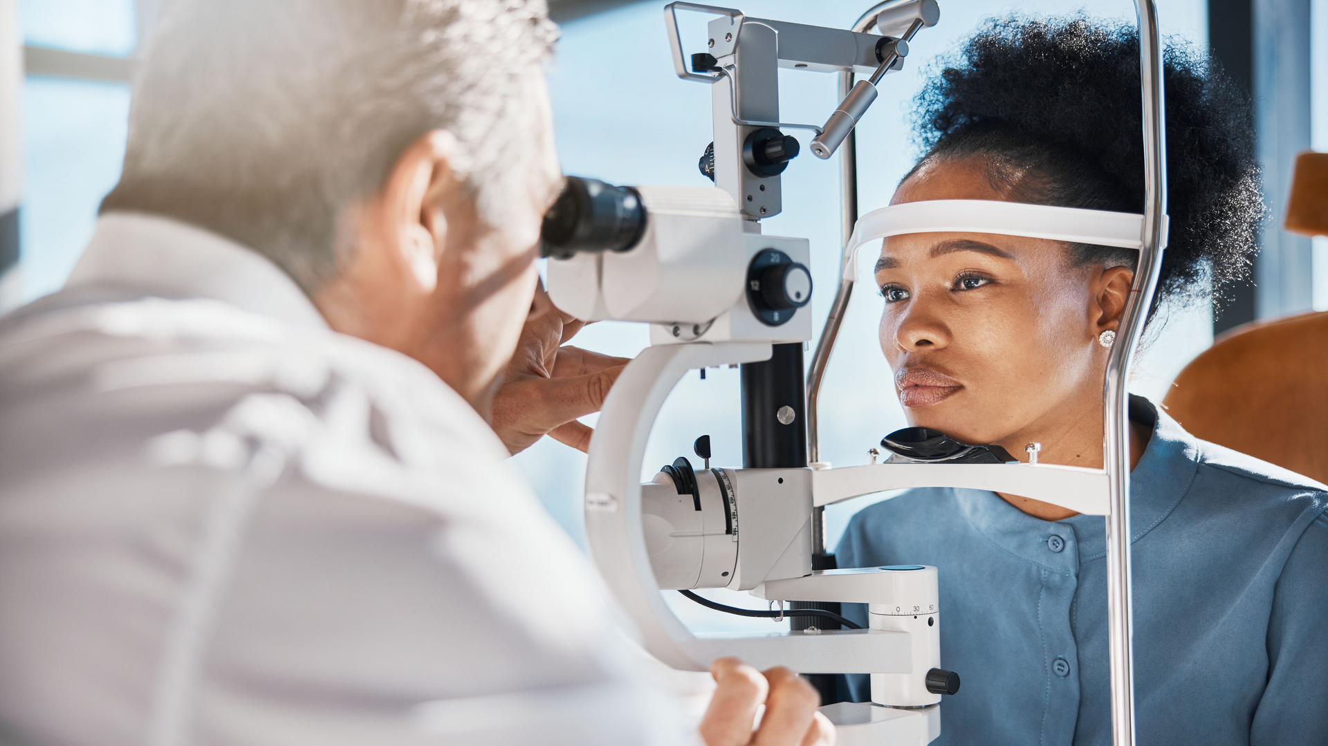 A little girl is getting her eyes checked by an ophthalmologist.