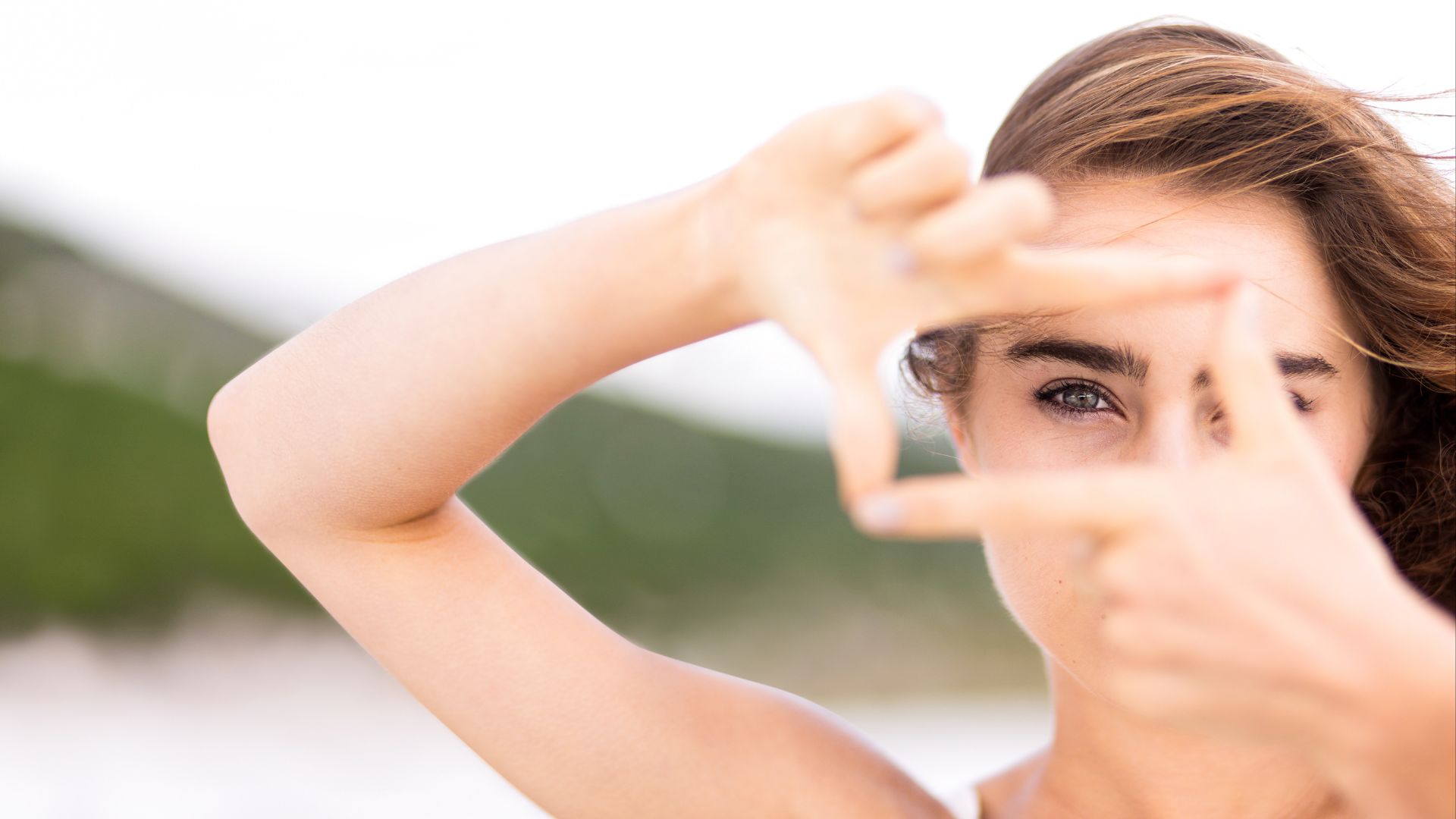 A woman is making a frame with her hands around her face.