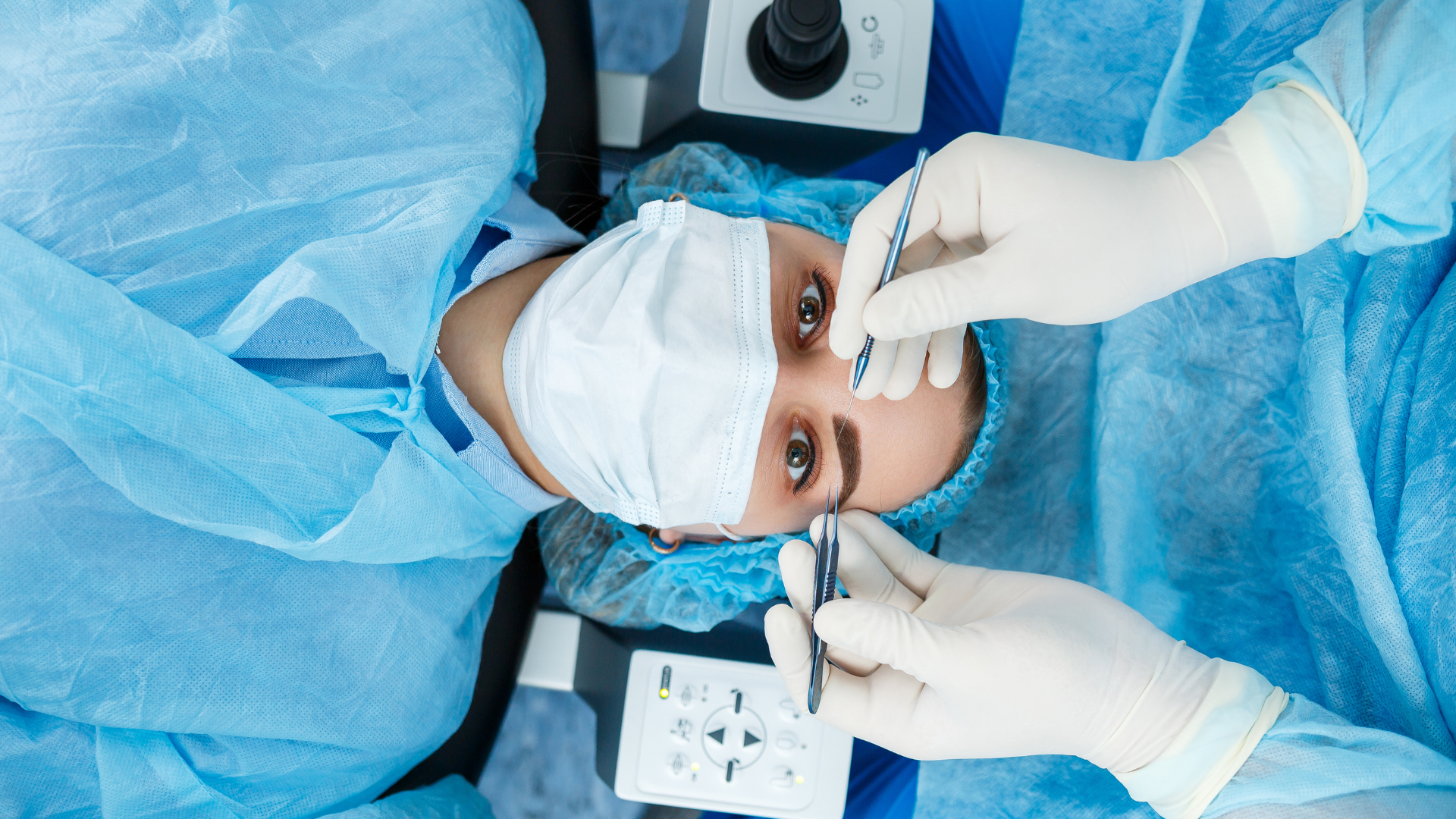 A surgeon is examining a patient 's eye under a microscope.