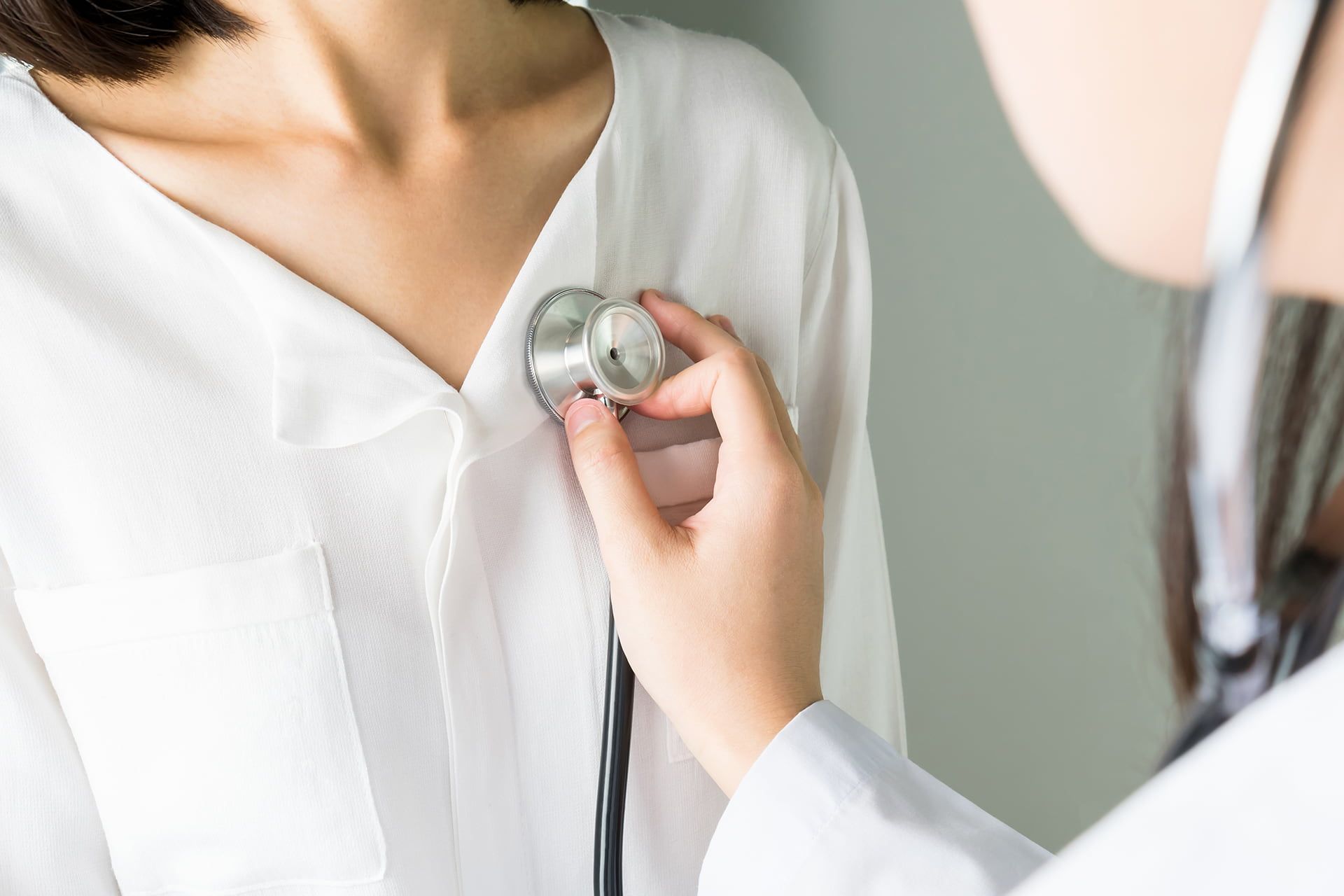 A Doctor Is Listening To A Woman's Heart With A Stethoscope — Rural Medical Clinic In Manilla, NSW