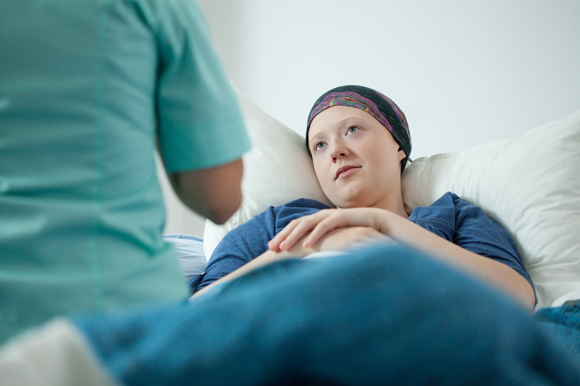 A Woman with Cancer Is Laying In A Hospital Bed Talking To A Nurse — Rural Medical Clinic In Manilla, NSW