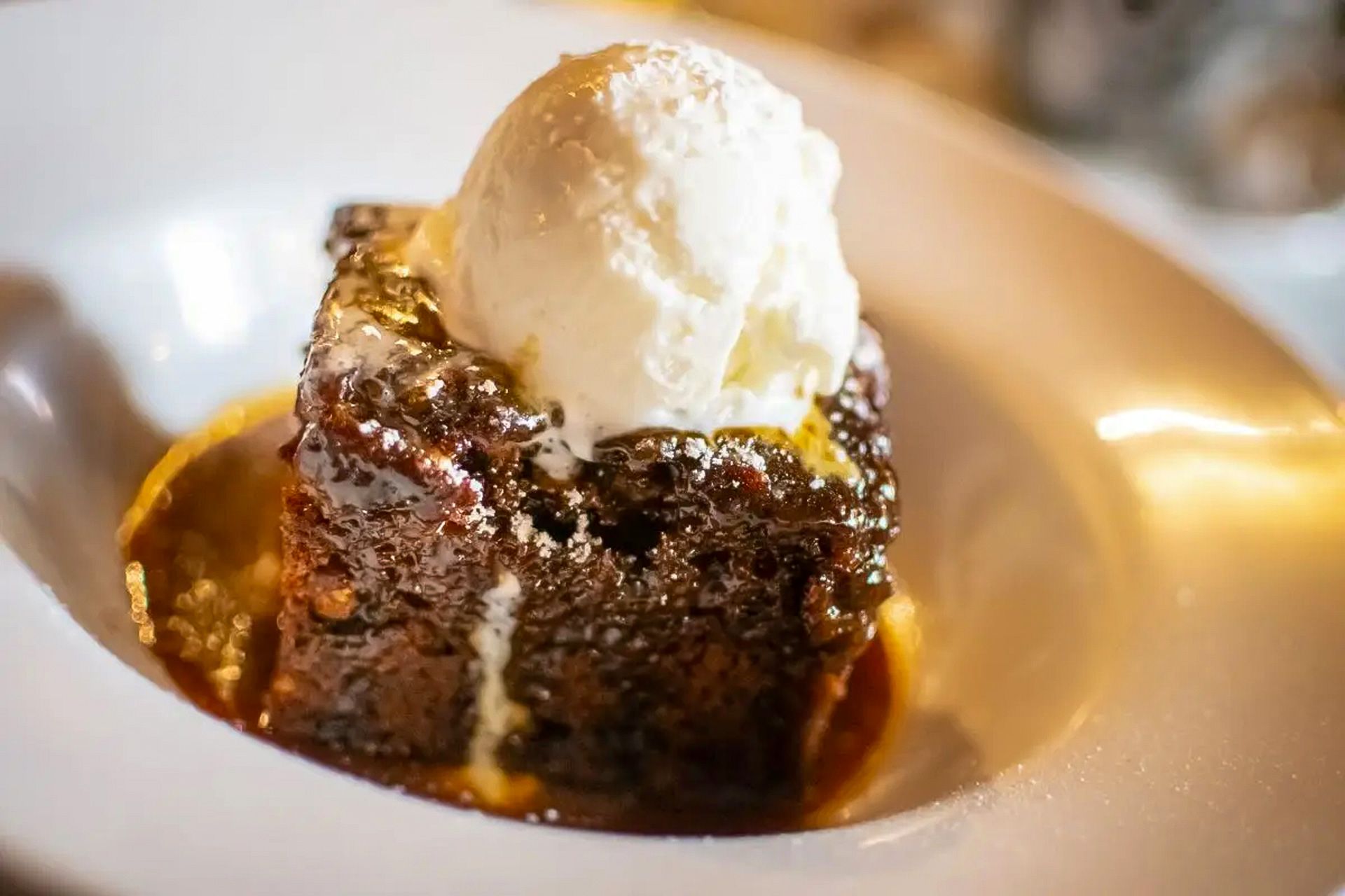 Sticky date pudding with ice cream on top of it in a bowl.