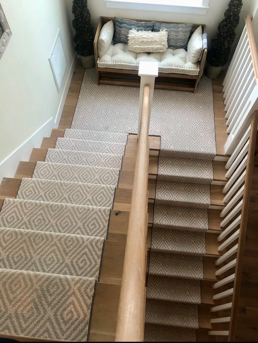 A staircase with a rug on the steps and a bench in the background.