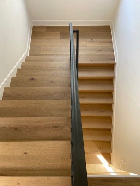 A wooden staircase with a black railing in a house.