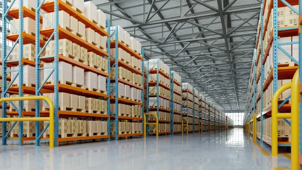 Large warehouse interior with tall orange-and-blue shelving aisles filled with boxes
