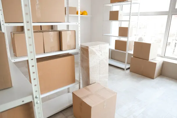 Boxes stacked on white shelves in a bright, empty storage room