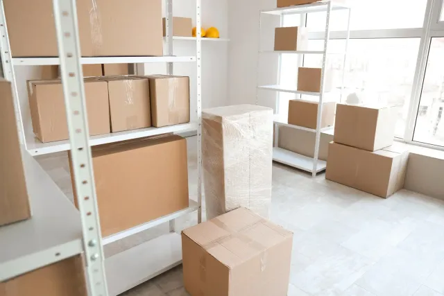 Boxes stacked on white shelves in a bright, empty storage room