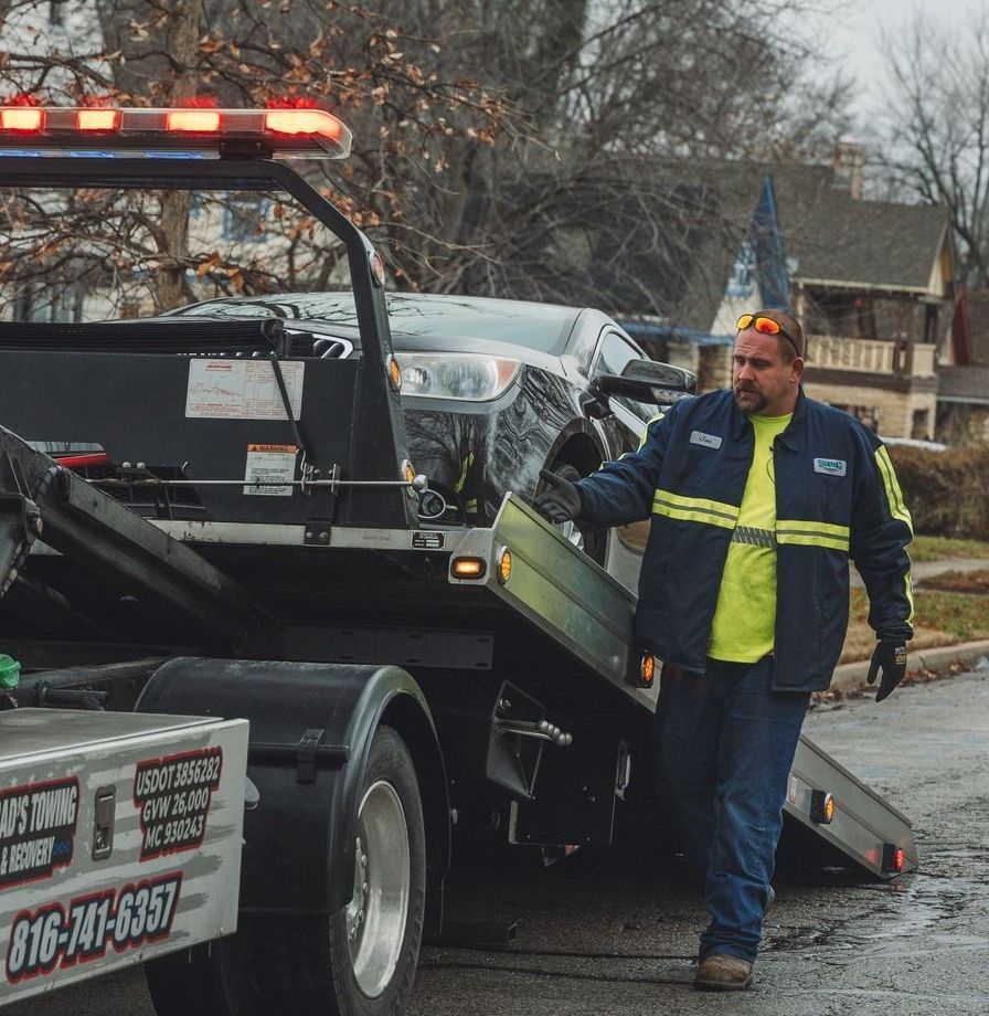 A tow truck is towing a car on a flatbed trailer.