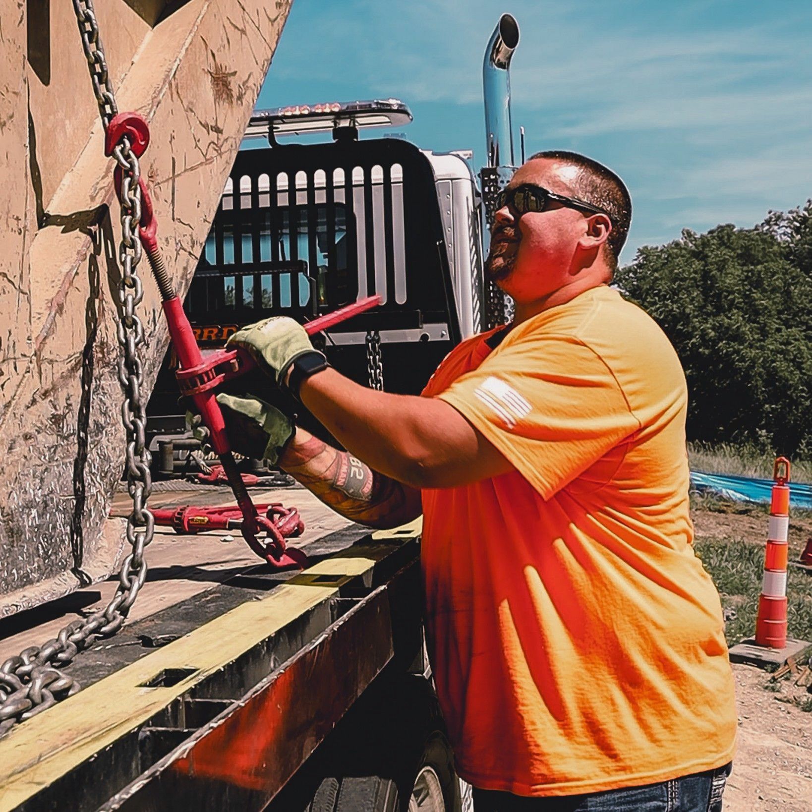 A man in an orange shirt is working on a truck