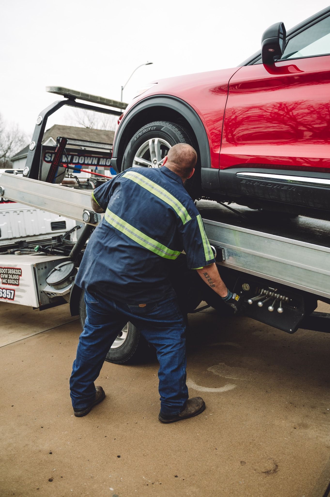 A man is walking towards a braud 's tow truck