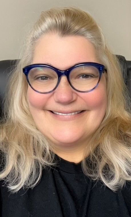 A woman wearing glasses and a black shirt is smiling.