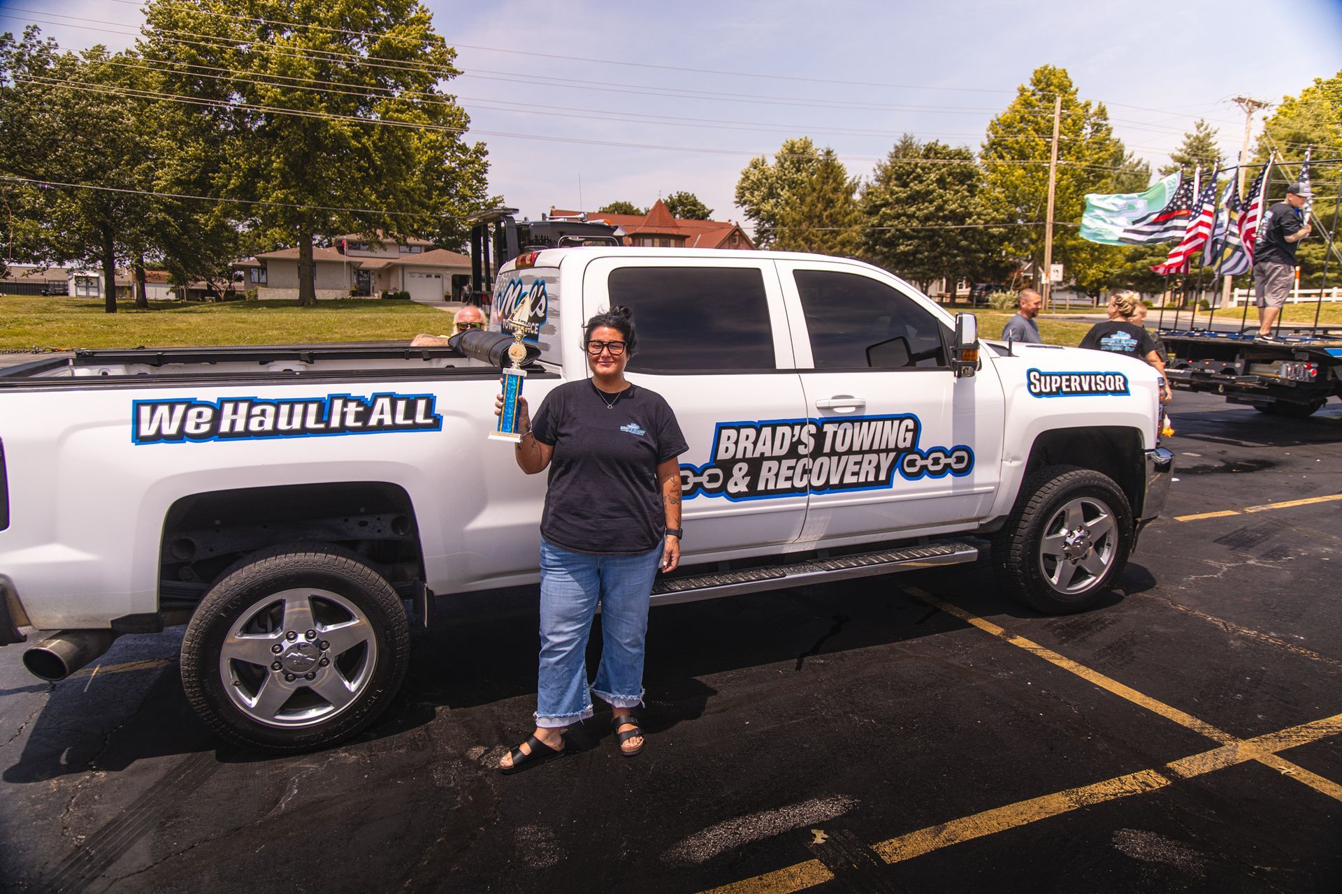 A woman stands in front of a truck that says we have it all