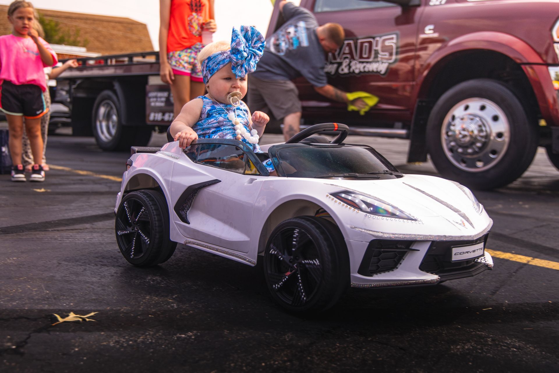 A little girl is sitting in a white toy car.