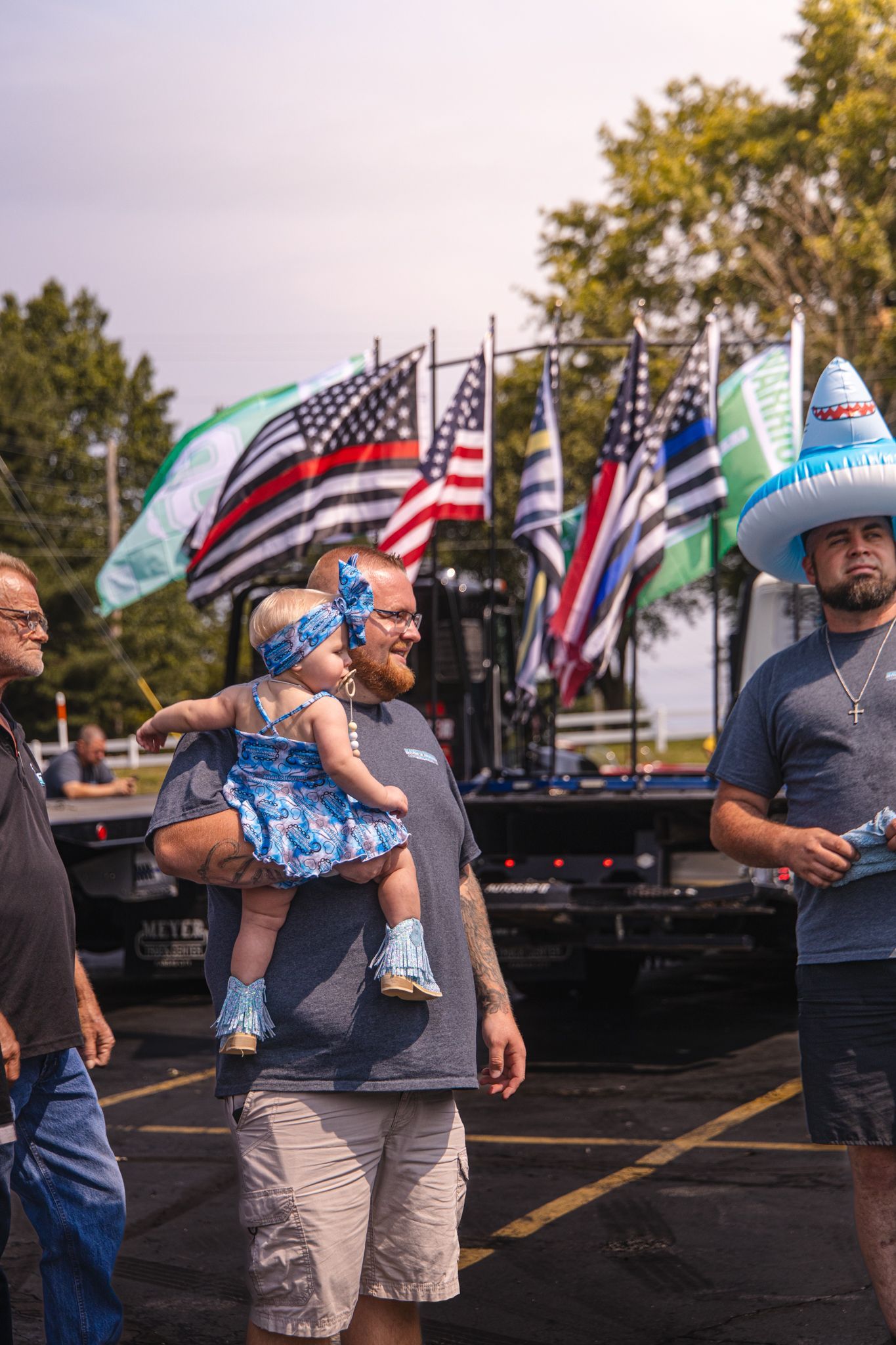 A man is holding a baby in his arms in a parking lot.