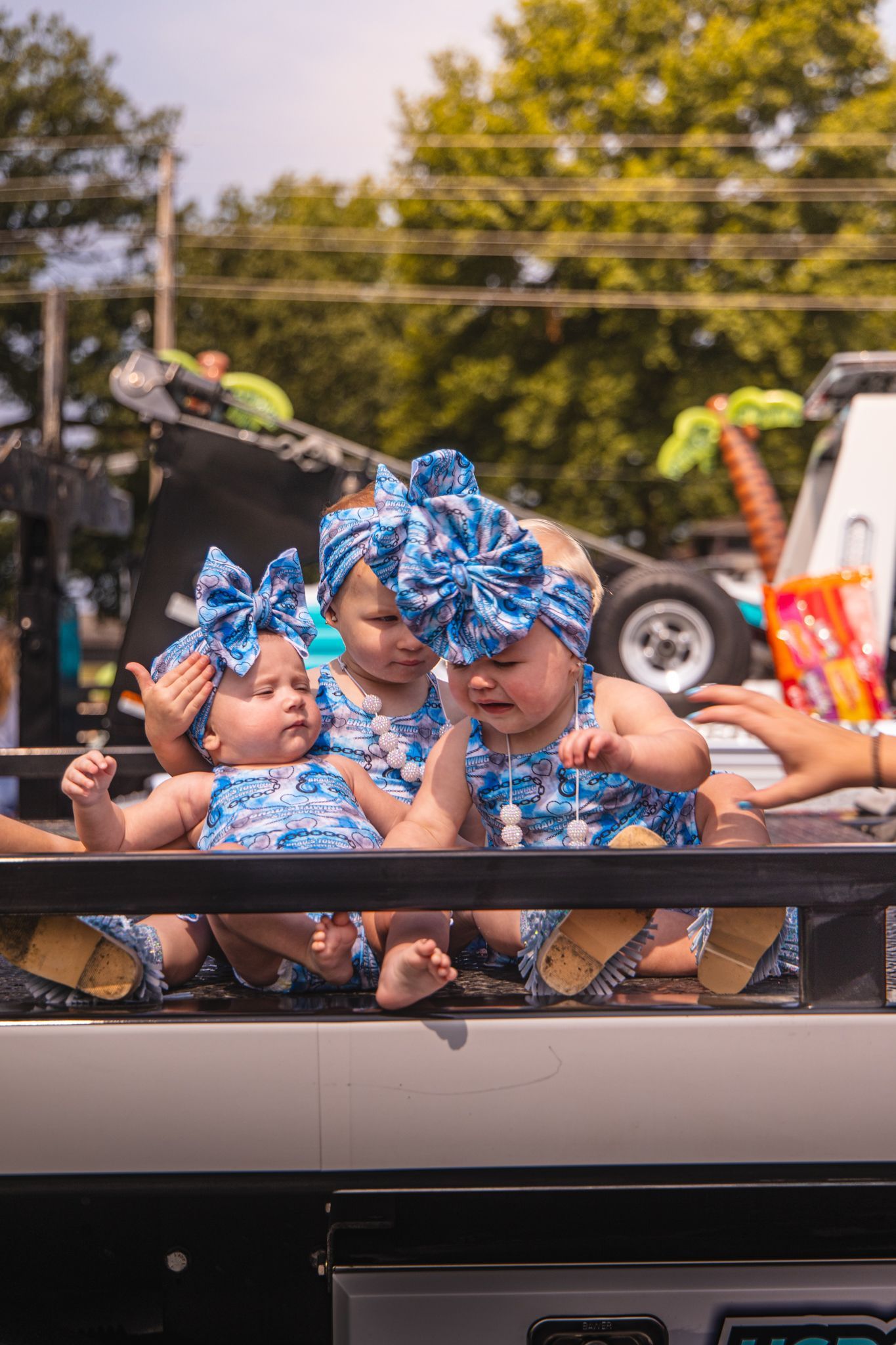 Three babies are sitting in the back of a truck.