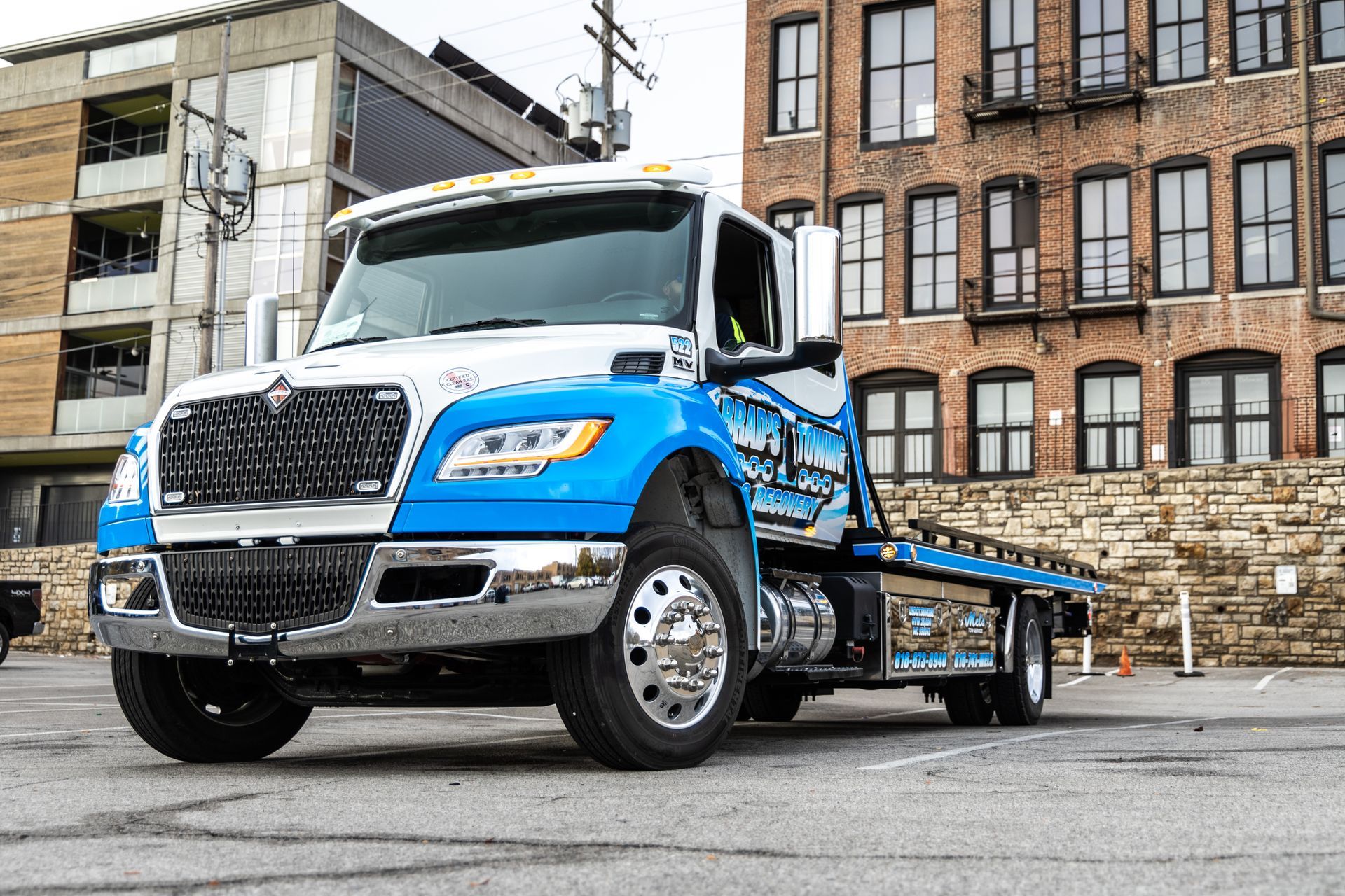 A blue and white tow truck is parked in front of a building.