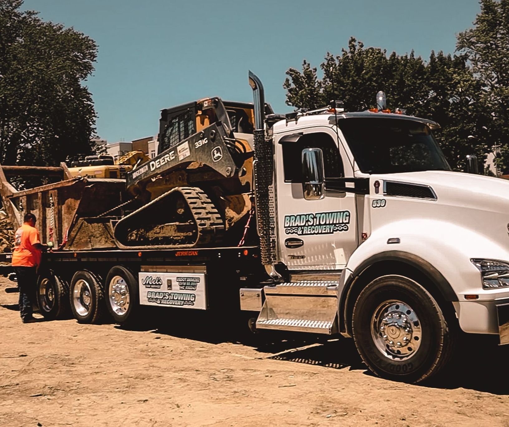 A white truck with a bulldozer on the back of it