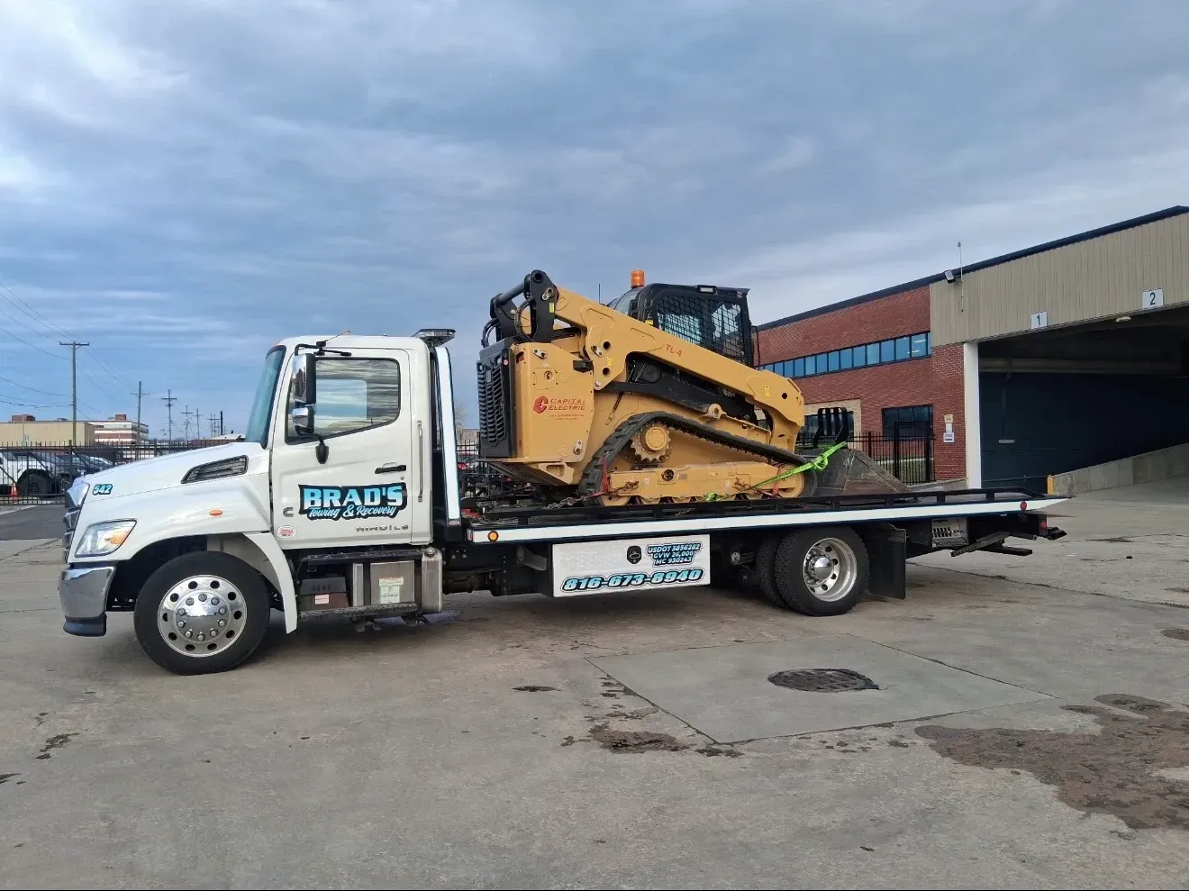 A man is standing in front of a tow truck that says tow truck