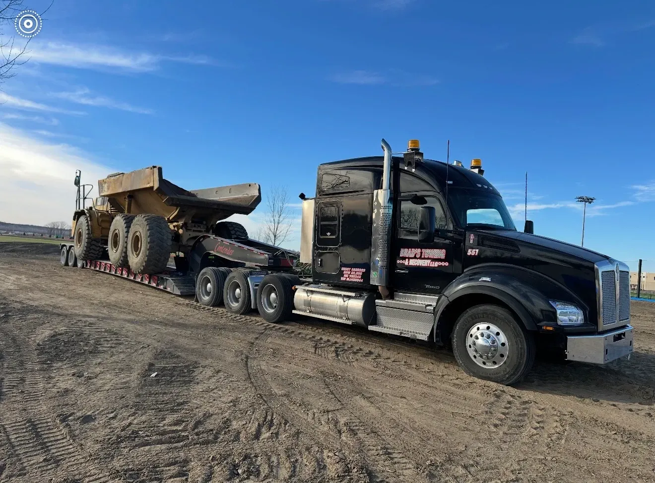 A man is standing in front of a tow truck that says tow truck