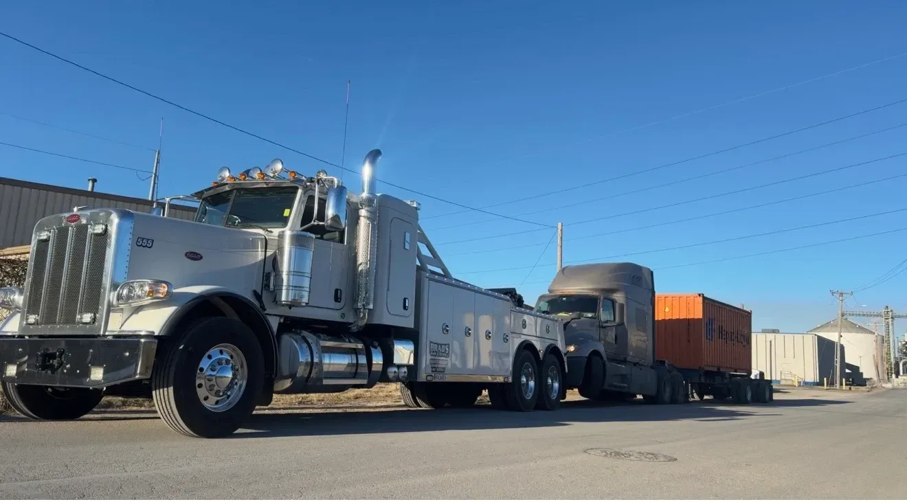 A man is standing in front of a tow truck that says tow truck