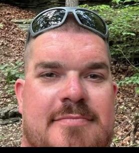 A man with a beard is wearing sunglasses on his head.