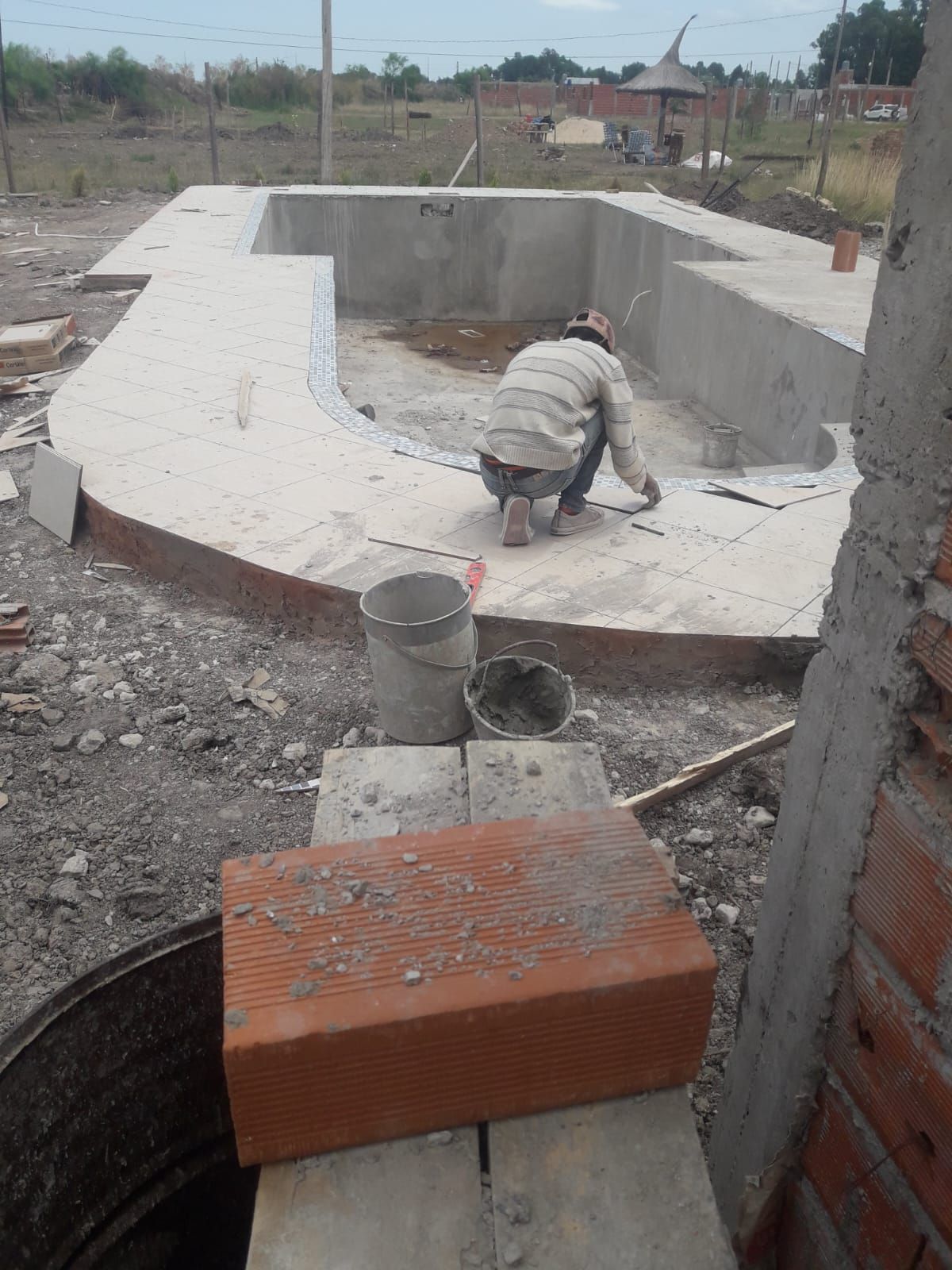 Un hombre está trabajando al borde de una piscina.
