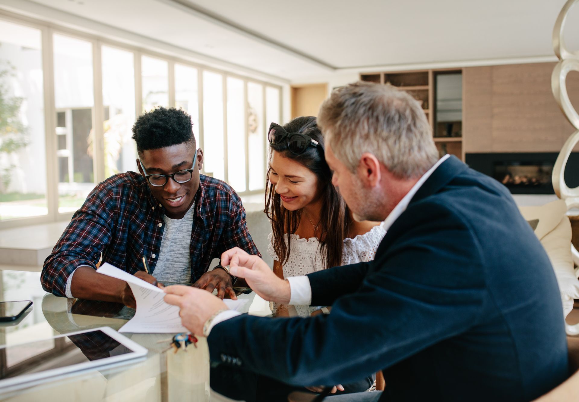 Couple reviewing paperwork with a professional at a table indoors.