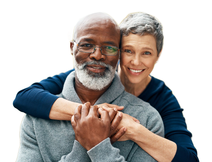 Smiling couple embracing outdoors. Woman leans head on man’s shoulder. They both laugh.