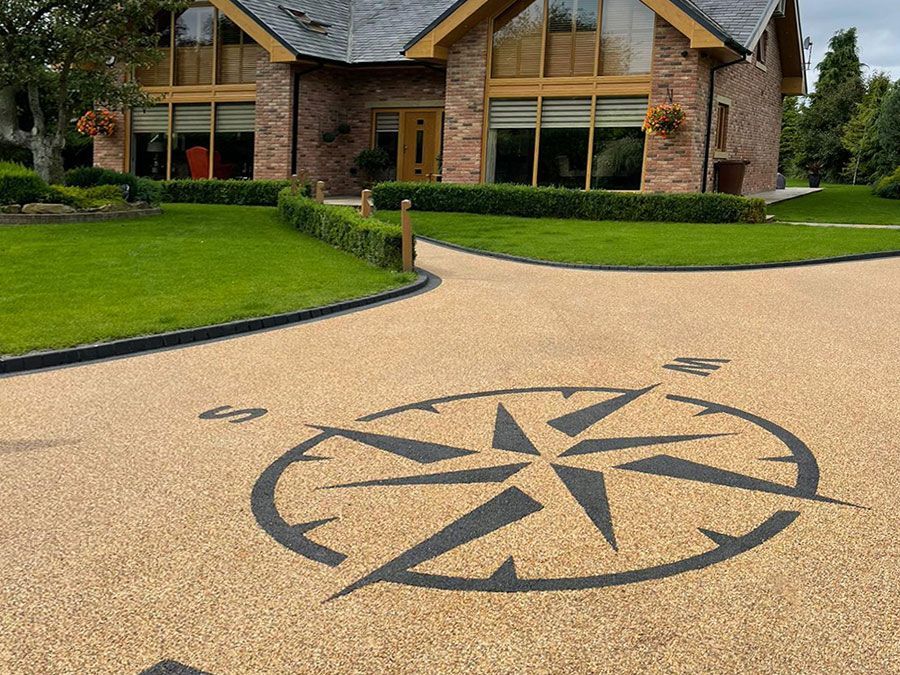 Black compass on a resin driveway with lawn in background.