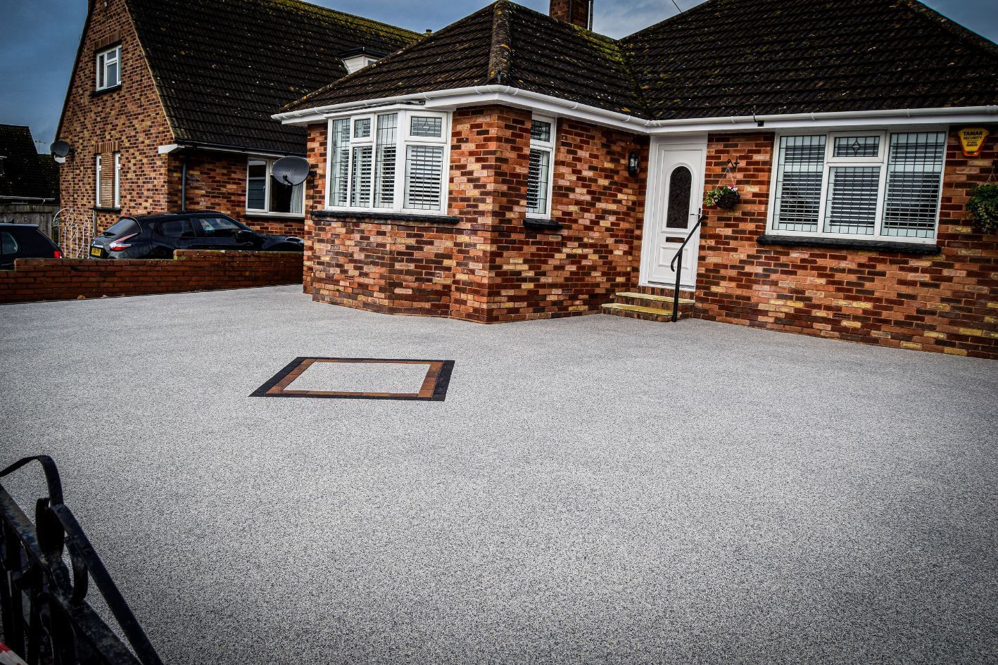 Grey resin driveway with a diamond shape in it.