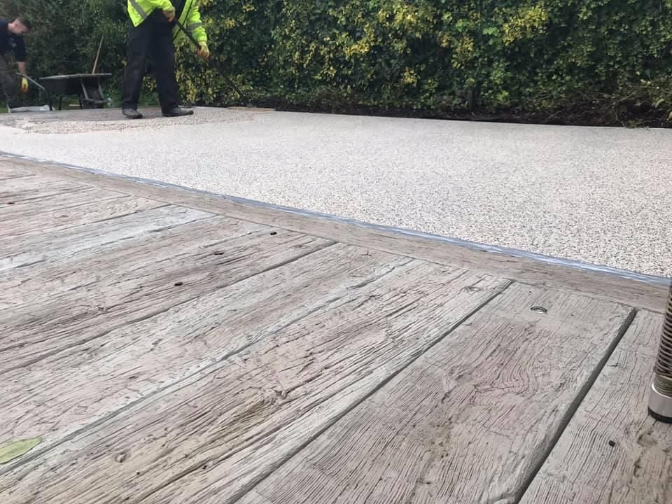 A man is laying concrete on a wooden deck.