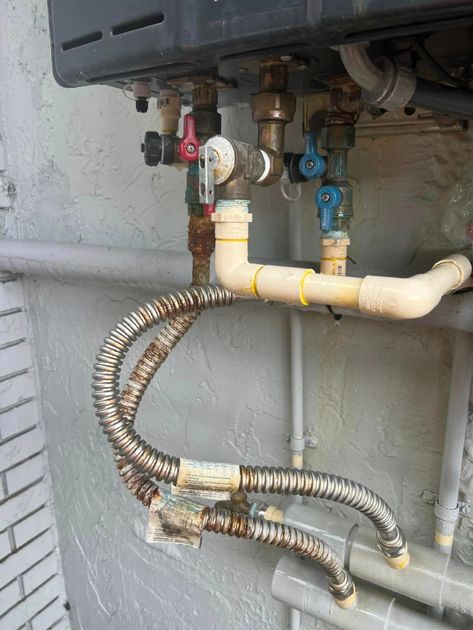 A close up of a water heater with a hose attached to it.