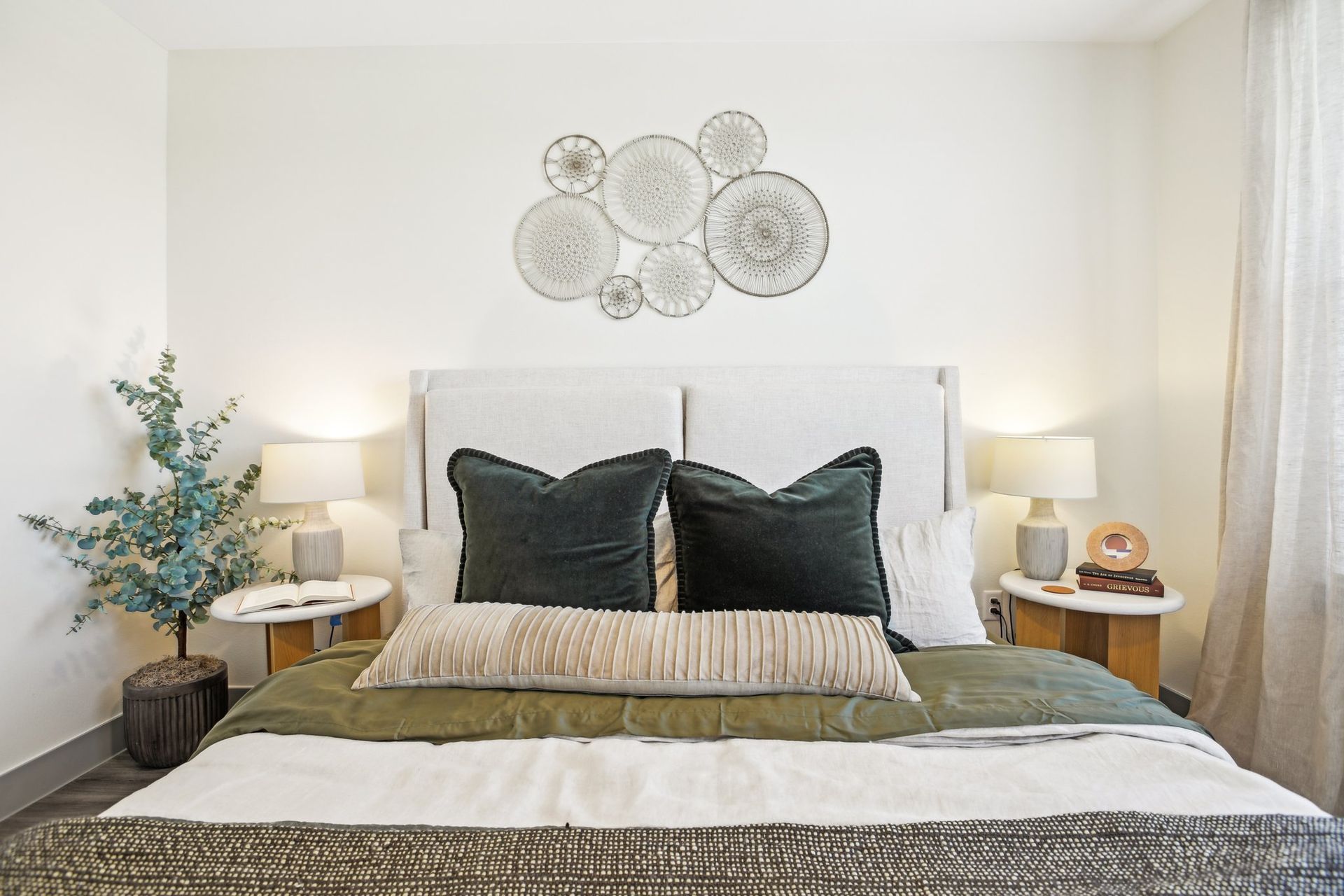 A bed with white sheets and wall decal above headboard
