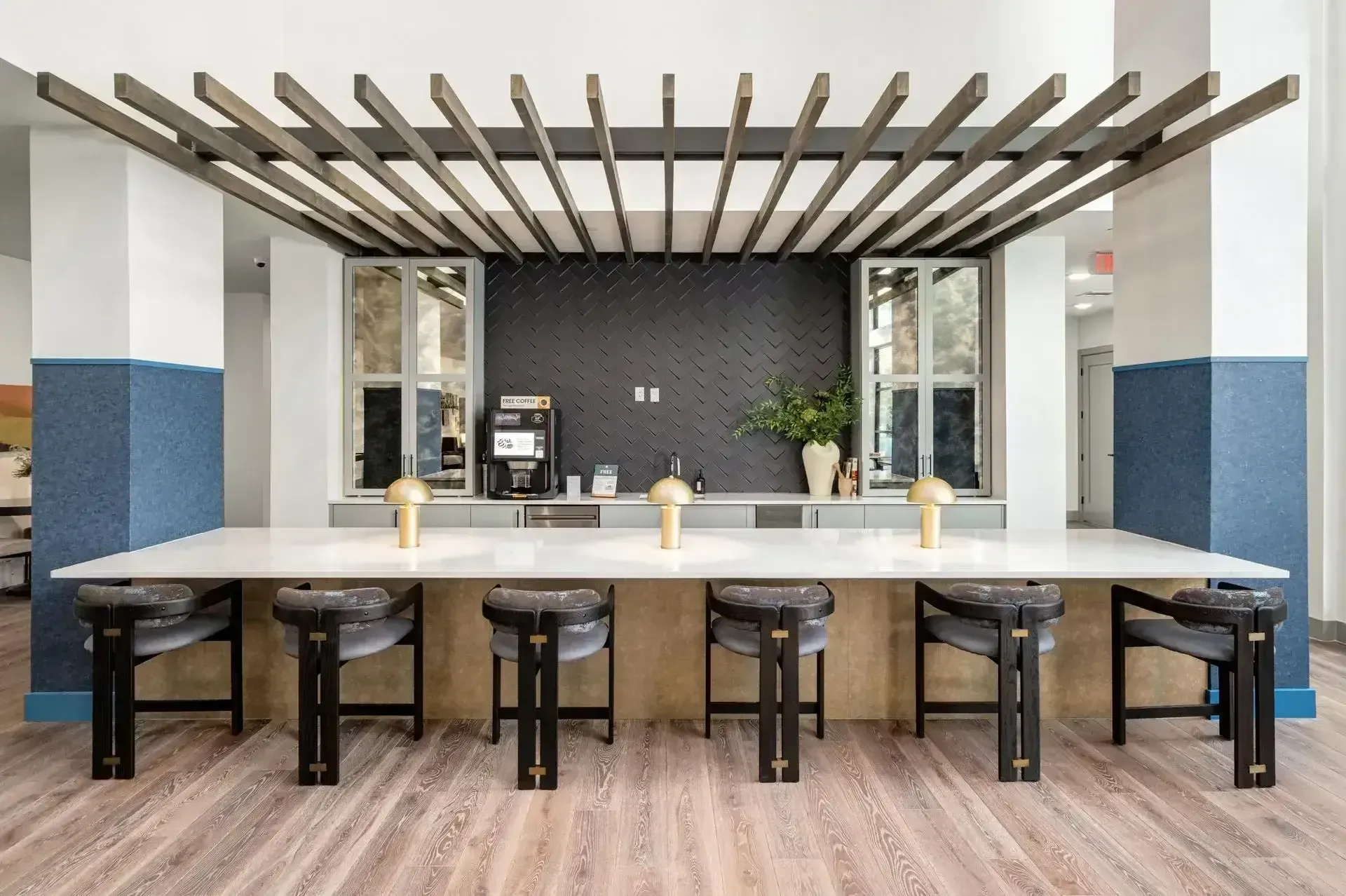 A kitchen with a long table and stools under a pergola at The Anderson 