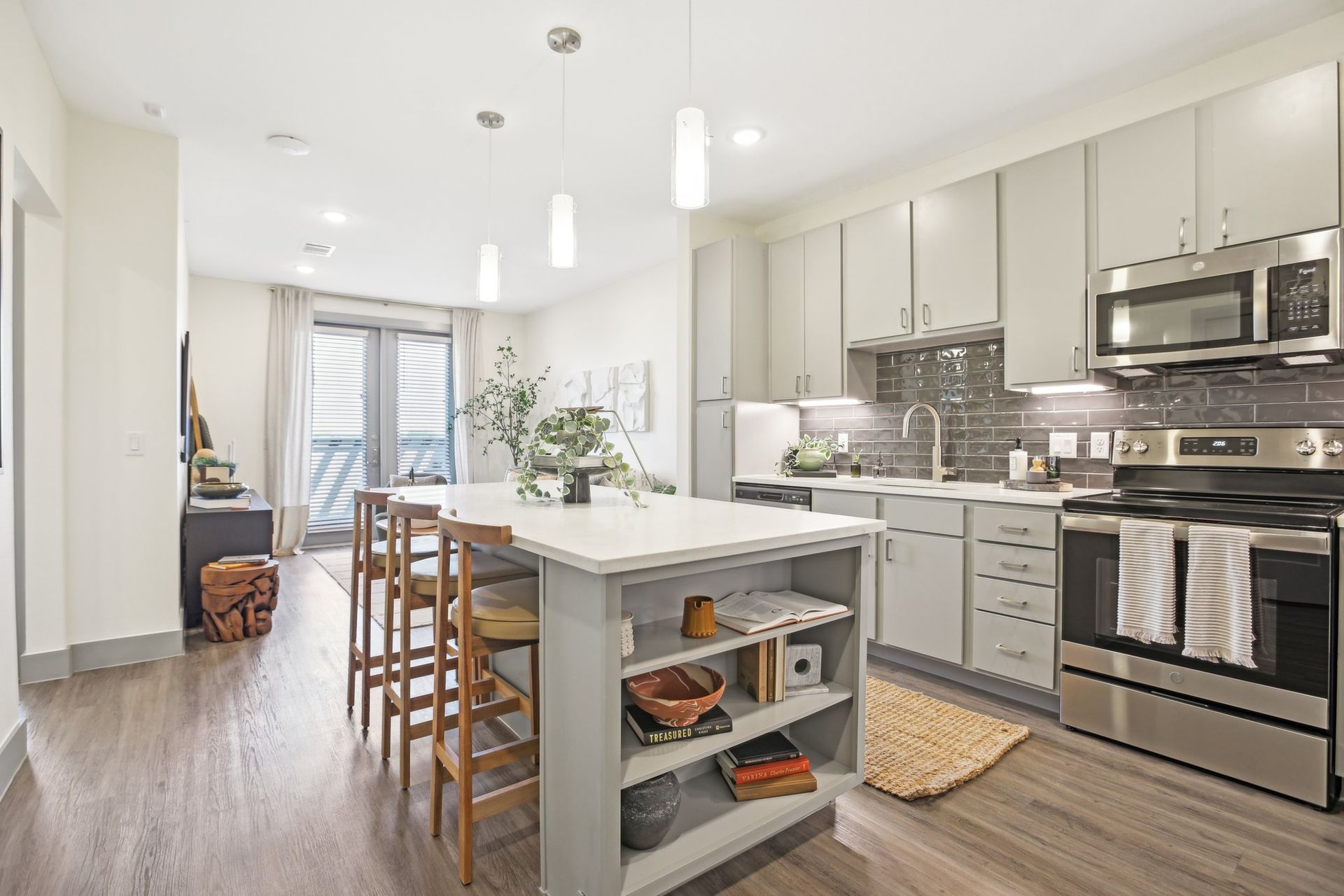 Modern kitchen with light gray cabinets, stainless steel appliances, and a kitchen island with bar stools.