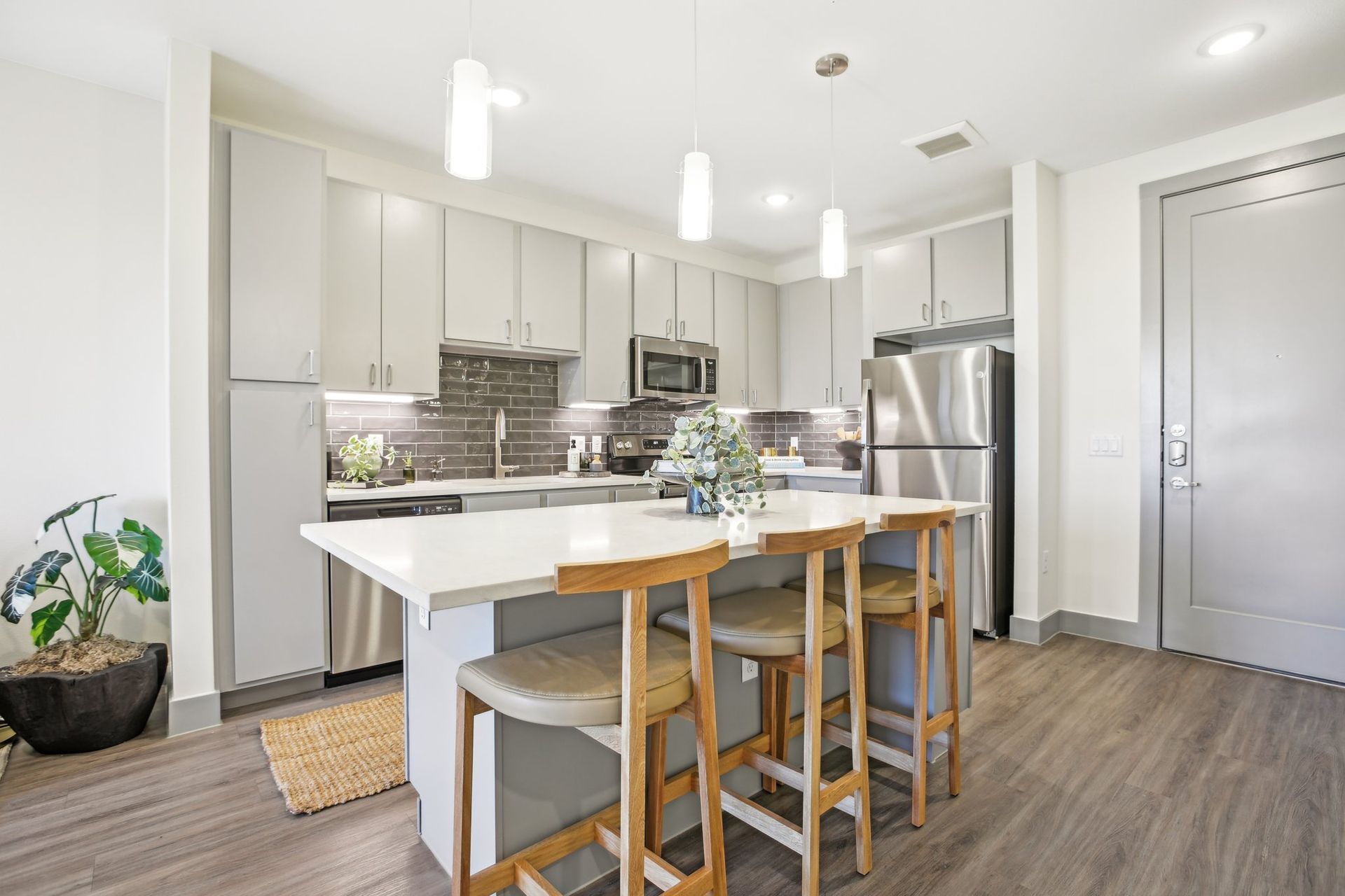 One bedroom kitchen with ample cabinet space with dark subway tile backsplash