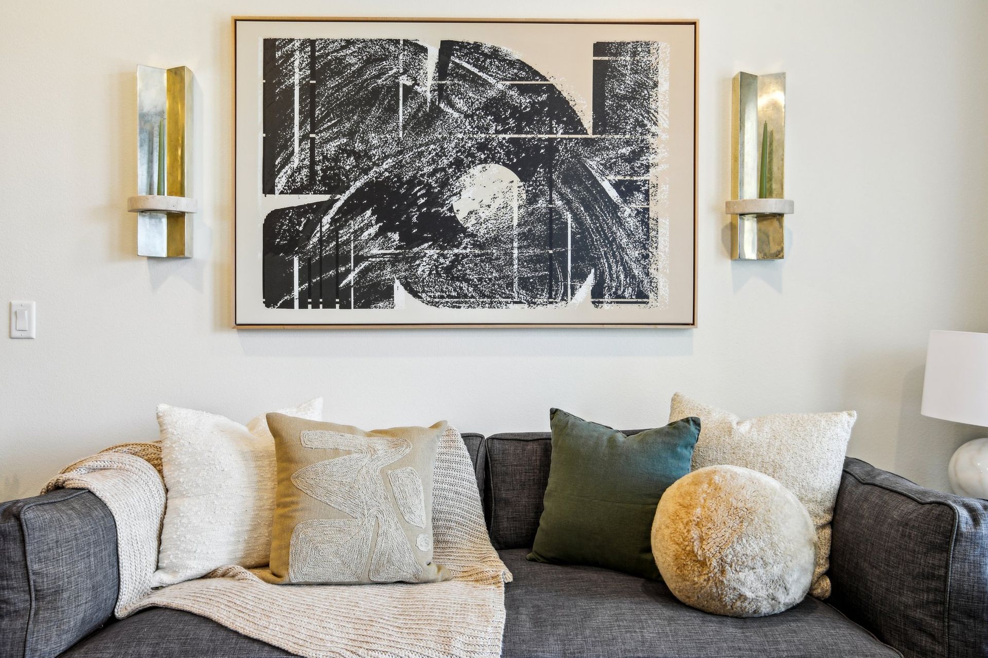 a gray couch with a painting above it