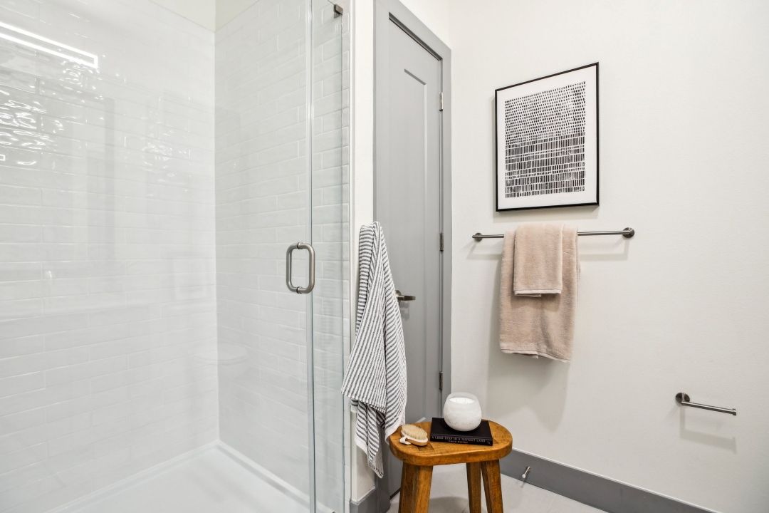 A bathroom with a walk in shower and a wooden stool.