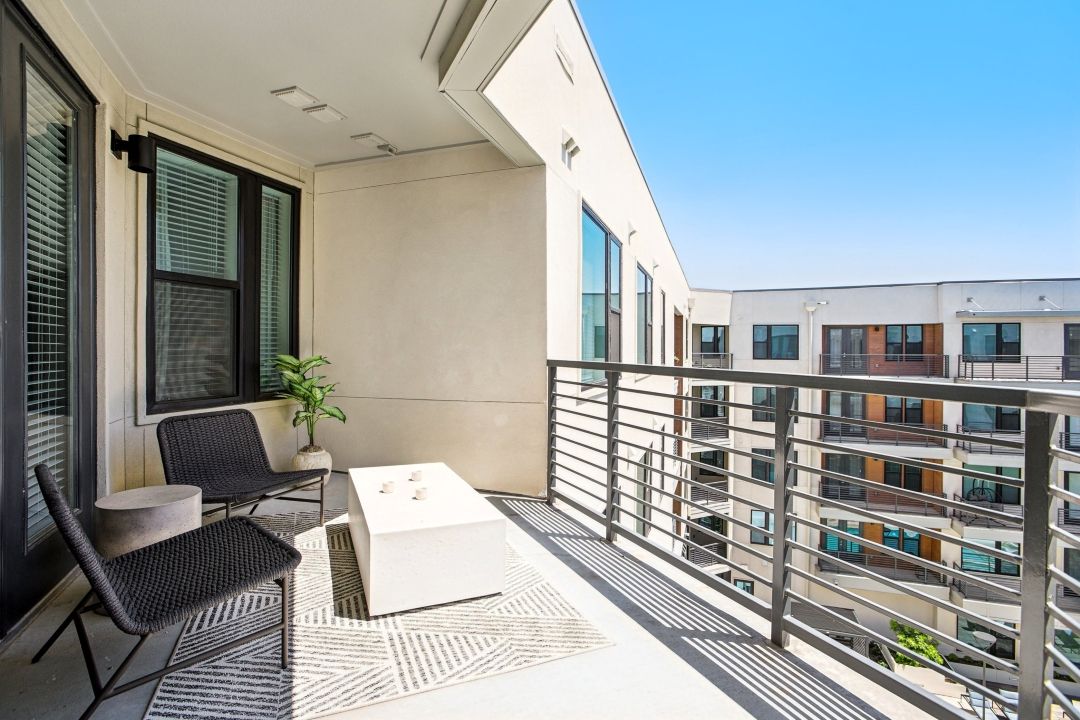 There is a balcony with chairs and a table on it.