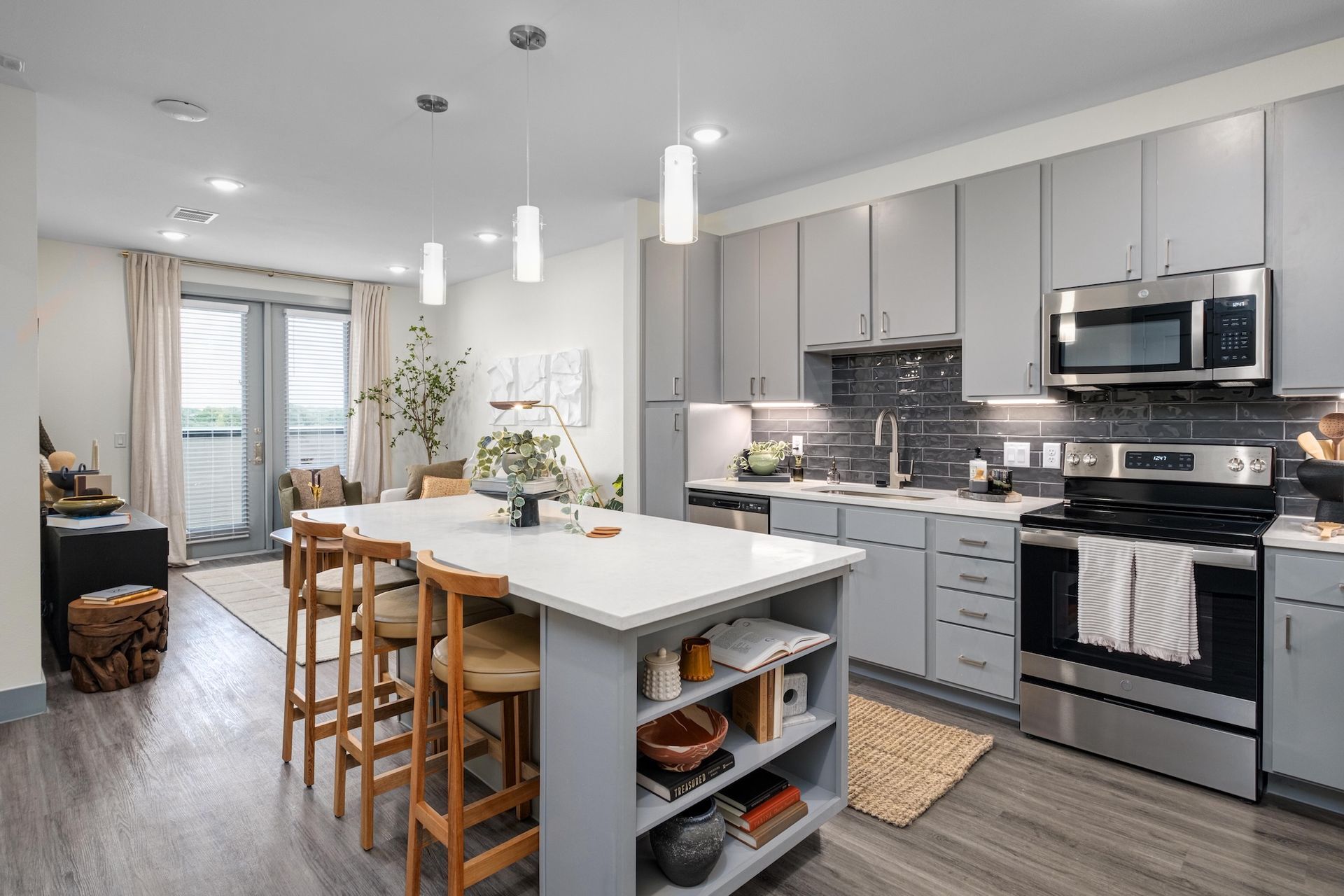 Modern kitchen with gray cabinets, white island, and stainless steel appliances.